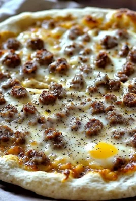 Delicious sausage gravy pizza topped with fluffy biscuits and creamy gravy