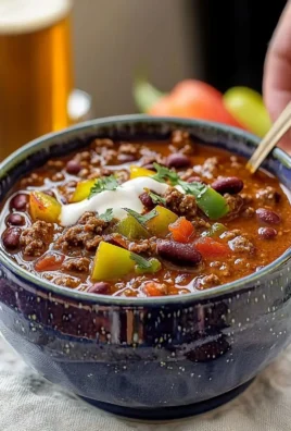 Bowl of chunky beef chili topped with cheese and cilantro