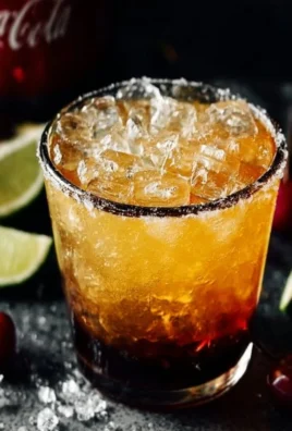 Cocktail glass filled with a Coca Cola Margarita garnished with lime