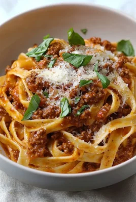 A delicious plate of creamy Fettuccine Bolognese topped with Parmesan cheese.