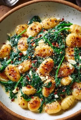 Creamy gnocchi dish with spinach and feta cheese garnished with herbs
