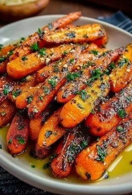 Honey Garlic Butter Roasted Carrots served on a plate garnished with herbs.