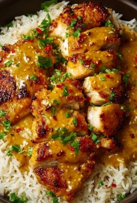 Honey Mustard Chicken served with rice on a plate, garnished with herbs.