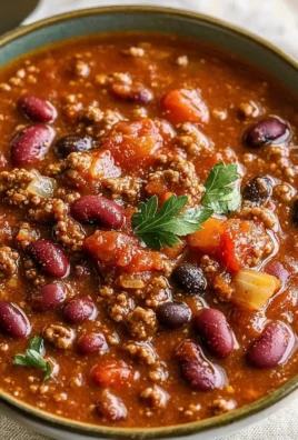 Bowl of old fashioned chili topped with cheese and herbs