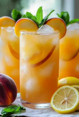 Glass of refreshing peach lemonade with fresh peach slices and lemon