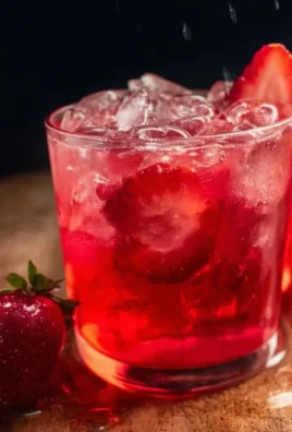 Glass of strawberry iced tea with fresh strawberries and mint leaves.