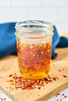 Homemade 3-Ingredient Hot Honey in a glass jar with chili peppers and honeycomb