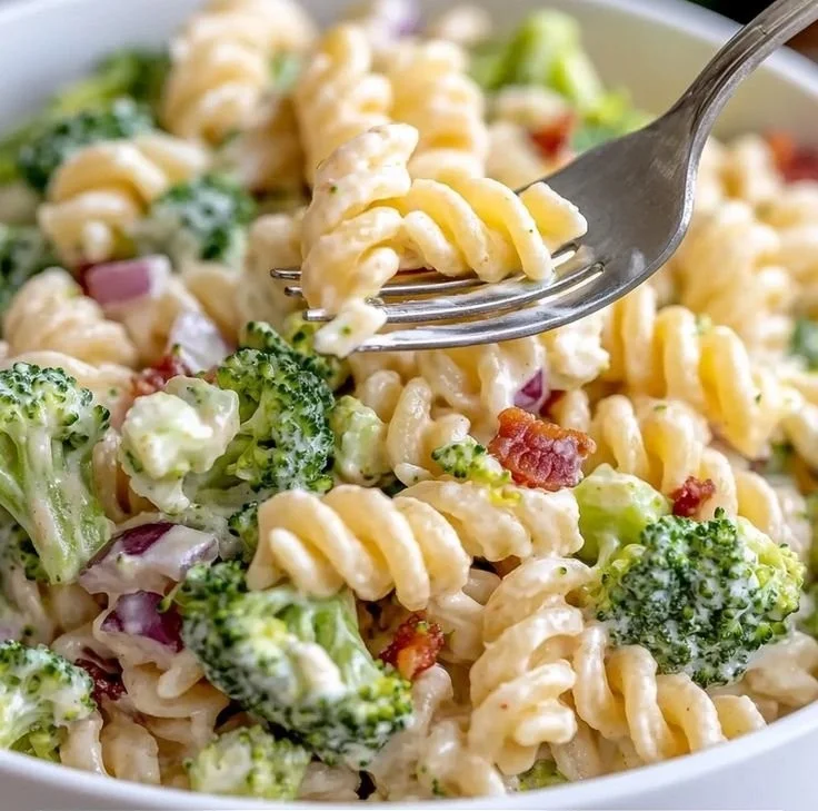 A vibrant bowl of broccoli pasta salad featuring fresh vegetables and dressing.