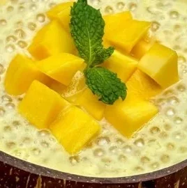 Delicious bowl of mango sago dessert topped with fresh mango and coconut