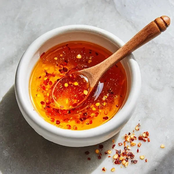 Bottle of Garlic Hot Honey with garlic cloves and chili peppers