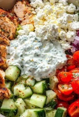 A colorful Greek chicken bowl with grilled chicken, fresh vegetables, and feta cheese.