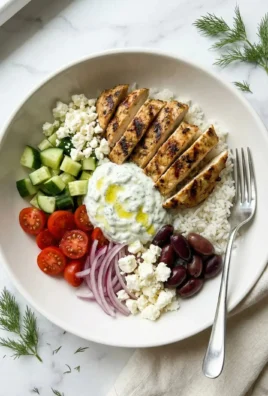 A colorful Greek Chicken Bowl filled with fresh vegetables and herbs.