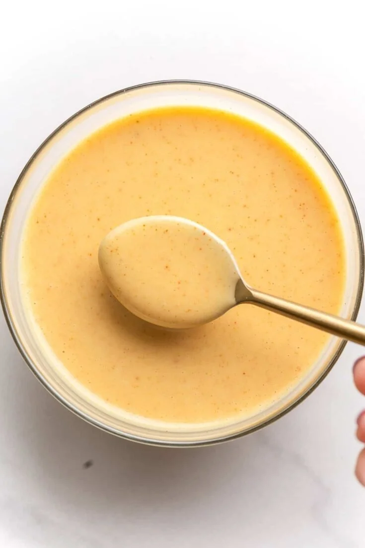 Delicious hot honey dipping sauce in a bowl with a honey dipper