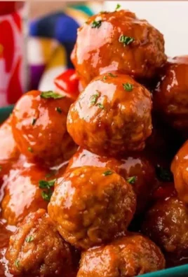 A platter of hot pepper jelly meatballs garnished with herbs.