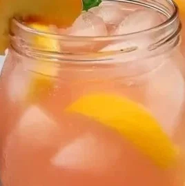 Glass of refreshing peach lemonade with fresh peaches and lemon slices