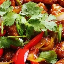 Delicious sweet chili chicken dish with vibrant sauce and garnishes.