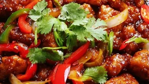 Delicious sweet chili chicken dish with vibrant sauce and garnishes.