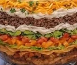Delicious seven-layer taco salad served in a bowl with vibrant toppings