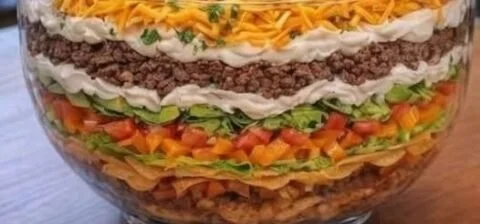 Delicious seven-layer taco salad served in a bowl with vibrant toppings
