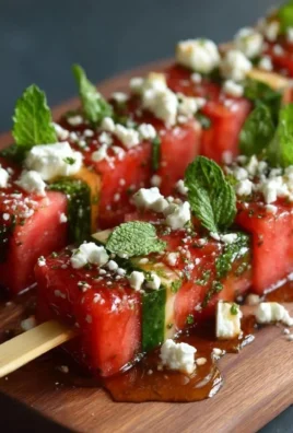 Delicious watermelon skewers featuring feta cheese and mint leaves.