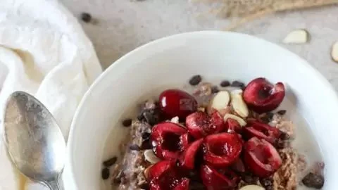 Chocolate cherry overnight oats in a bowl topped with fresh cherries and chocolate shavings