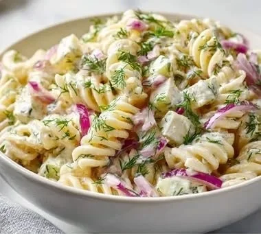 Creamy dill pickle pasta salad served in a bowl with fresh herbs