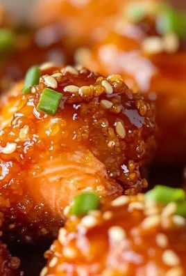 Crispy honey garlic salmon bites served on a plate, garnished with herbs.
