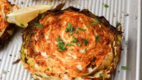 Oven roasted cabbage steaks topped with spices, served on a plate