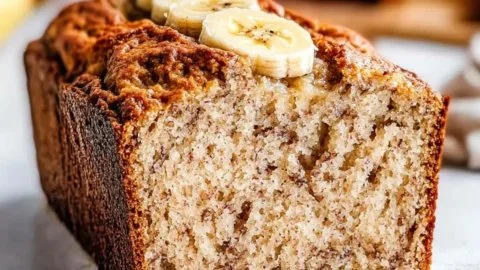 Healthy Greek yogurt banana bread slice on a plate with ripe bananas