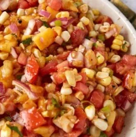 Bowl of homemade peach salsa with corn served with tortilla chips