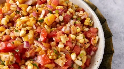 Bowl of homemade peach salsa with corn served with tortilla chips