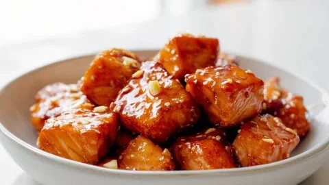 Honey Garlic Salmon Bites served on a platter with fresh herbs.