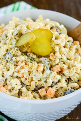 Pasta salad with dill pickles, vegetables, and dressing in a bowl