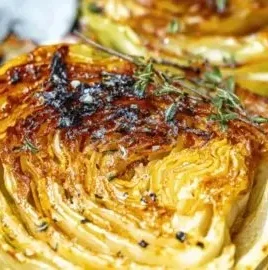 Roasted cabbage steaks on a plate, garnished with herbs and spices
