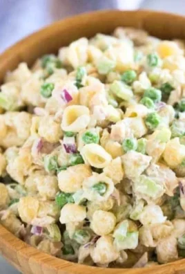 A vibrant bowl of Tuna Pasta Salad with vegetables and dressing.