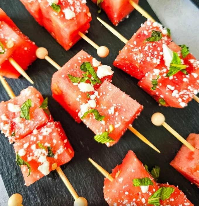 Colorful watermelon feta skewers with fresh herbs and a drizzle of balsamic glaze.