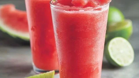 A vibrant watermelon strawberry slush served in a glass with mint garnish