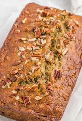 Delicious slice of Banana Pecan Bread topped with pecans and surrounded by bananas.