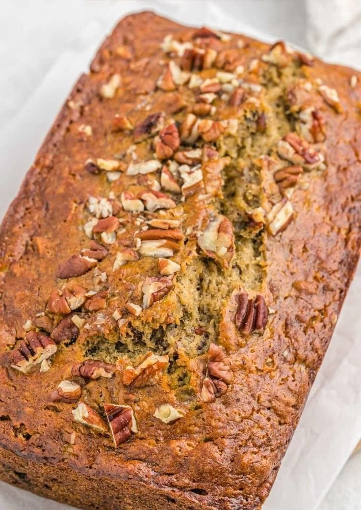 Delicious slice of Banana Pecan Bread topped with pecans and surrounded by bananas.