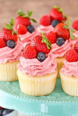 Delicious berries and cream cupcakes topped with fresh berries and whipped cream