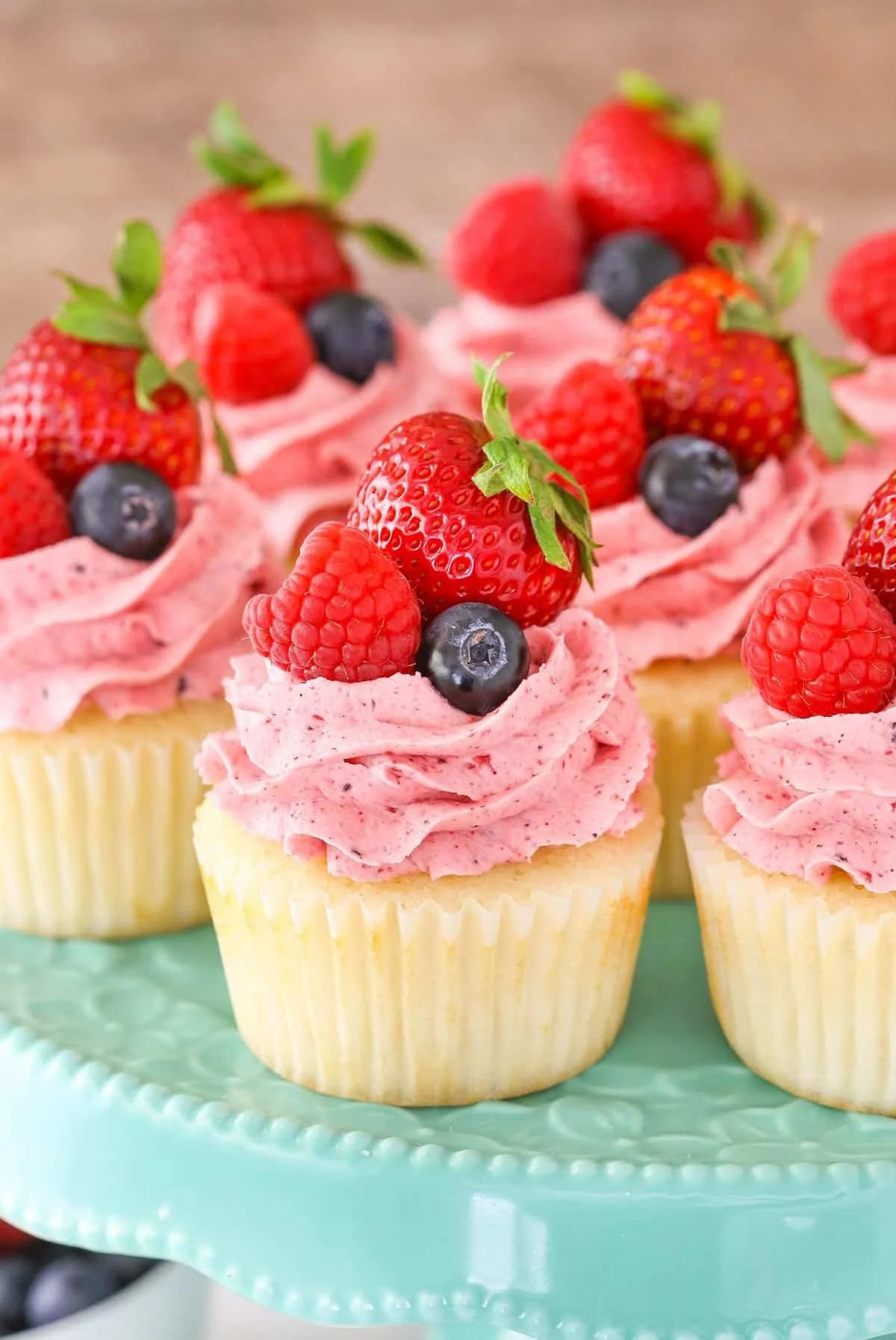 Delicious berries and cream cupcakes topped with fresh berries and whipped cream