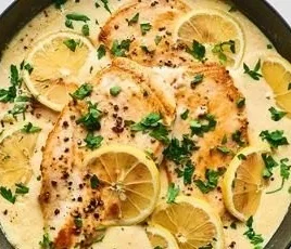 Creamy lemon garlic chicken on a plate garnished with herbs.