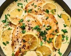 Creamy lemon garlic chicken on a plate garnished with herbs.