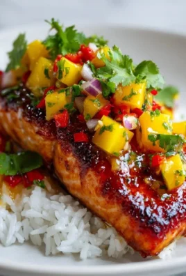 Grilled salmon fillet topped with fresh mango salsa on a plate