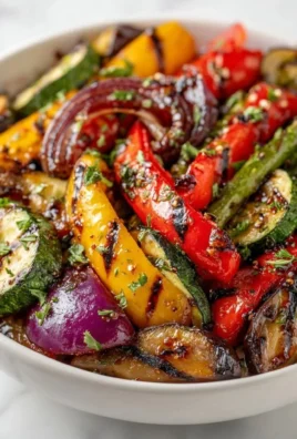Assorted grilled veggies including bell peppers, zucchini, and eggplant on a barbecue grill.