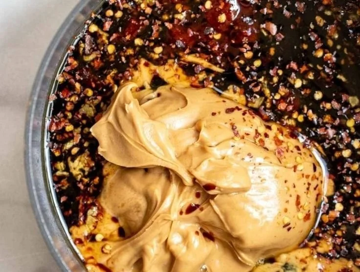 Spicy peanut butter noodles served in a bowl with chopsticks