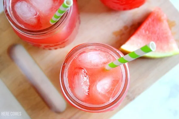 Refreshing watermelon lemonade served in a glass with lemon slices and mint.
